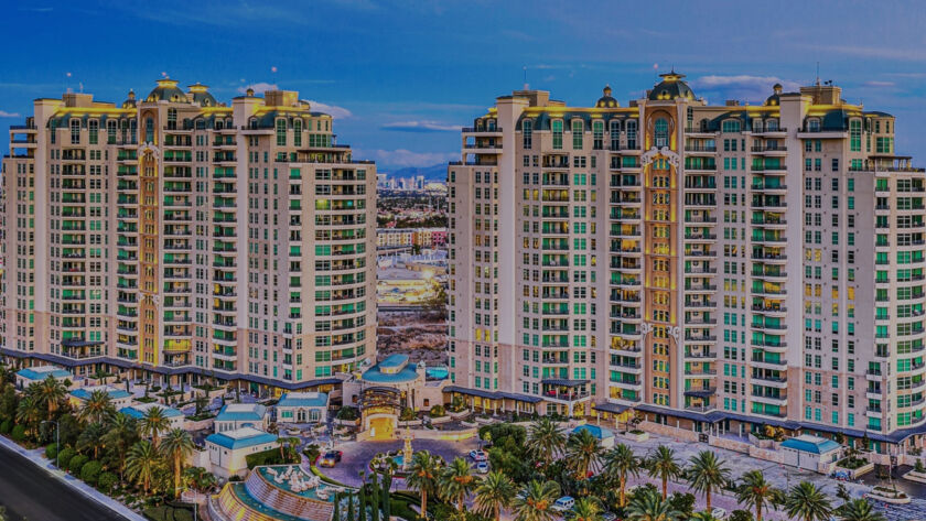 Exterior view of One Queensridge Place luxury residential towers in Las Vegas surrounded by palm trees at sunset